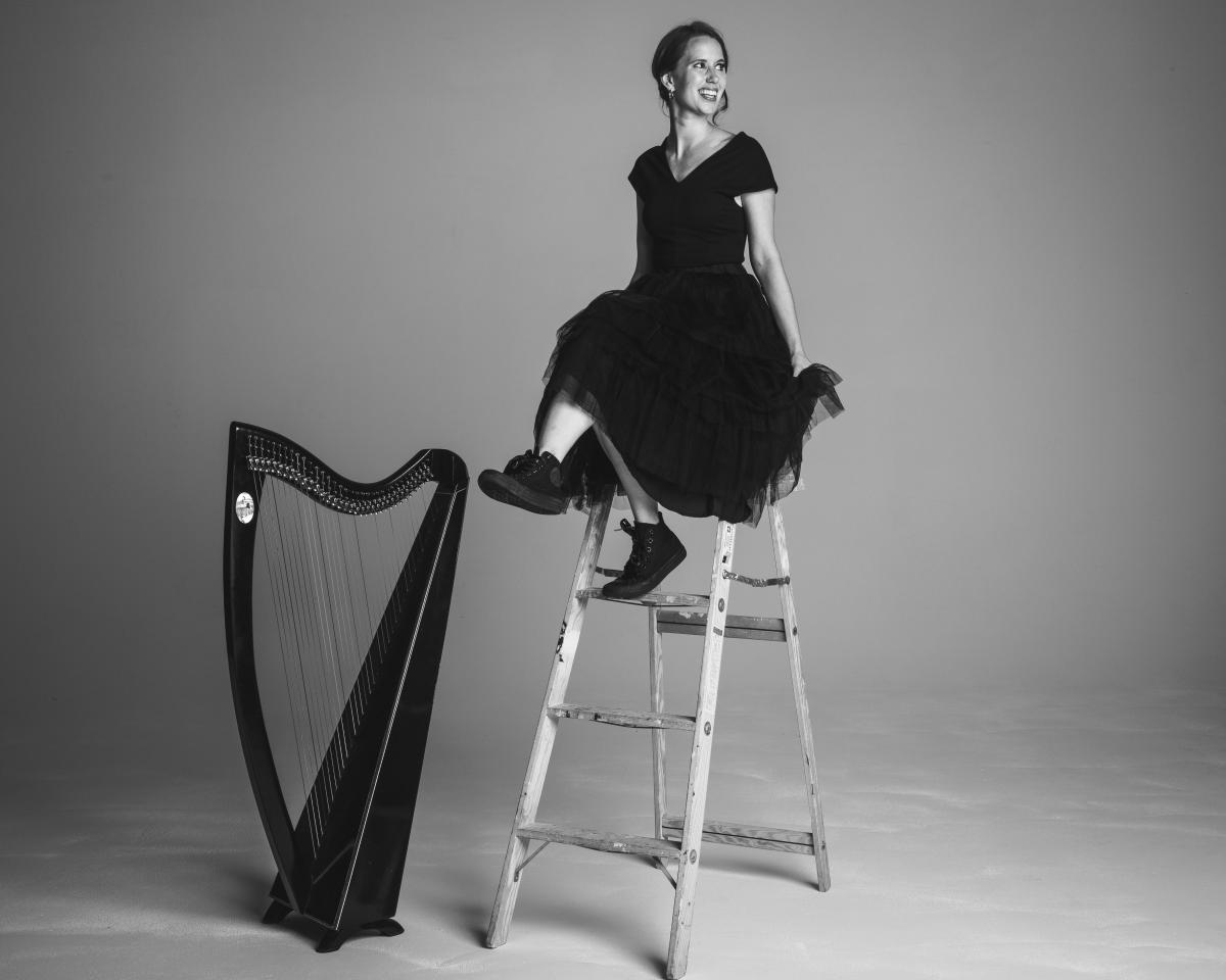 Maeve Gilchrist sits on a ladder next to a harp
