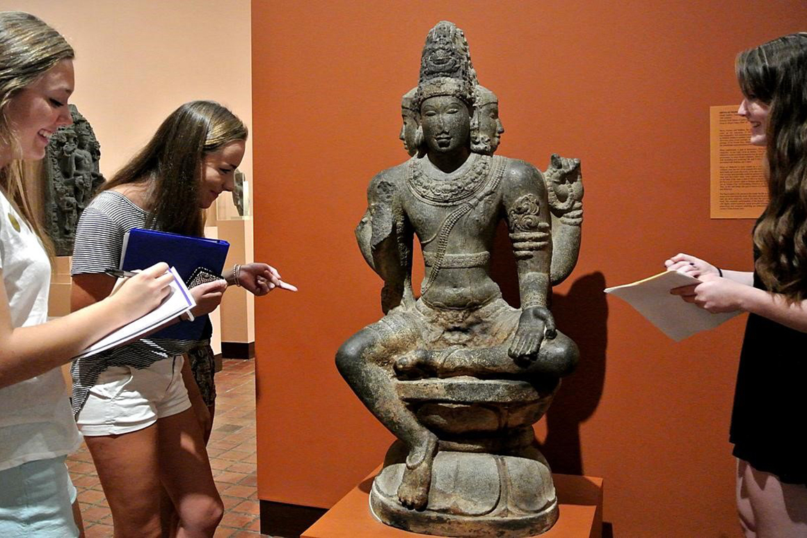 students looking at a statue in a museum