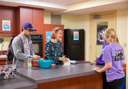 two students baking as two other students converse with them in kitchen basement of Clark Hall