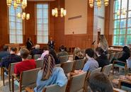 Congressman Jim McGovern, seated at the front of the room with Professor Thomas Ward, answers the question of a student at a microphone in the center aisle of the audience in Rehm Library.