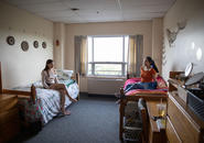 two students sitting on their beds chatting in their room in Loyola Hall