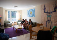 three students sitting on a couch playing a video game in their apartment in williams hall