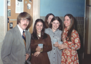 A color photo of 4 women and one man posing got a photo. Three of the women are seend with a plastic cupe of presumably beer in their hands and are smiling at the camera.