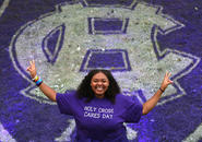 A student stands in front of the Holy Cross 175th logo painted on the grass. Photo by Tom Rettig