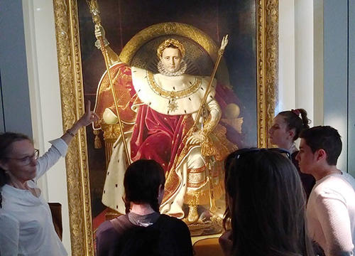 Professor Theresa McBride points out a painting to students at a museum in Paris.