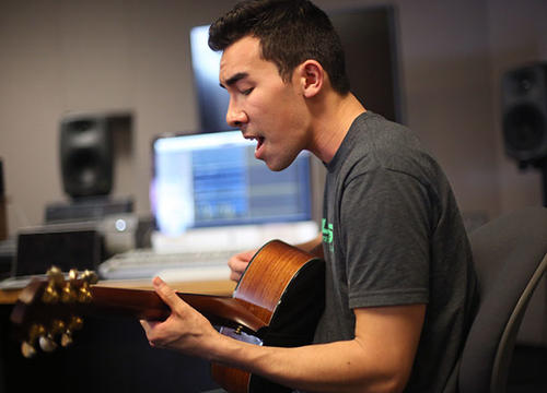 Nate Chung plays his guitar in the Brooks Digital Media Studio.