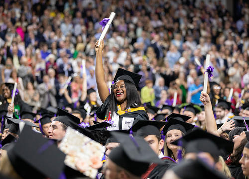 A graduating student waves her diploma at the 2019 Holy Cross graduation.