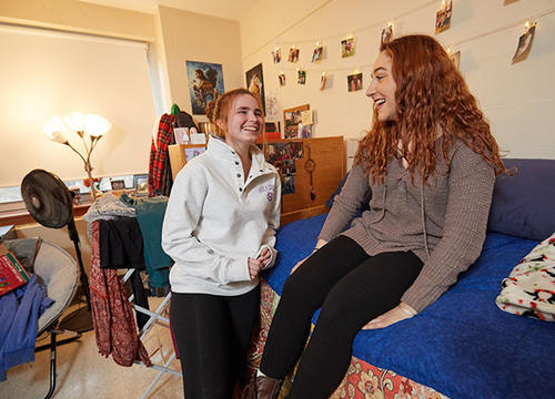 Abby Connolly '22 and Grace Acquilano '22 stand and laugh in their dorm room