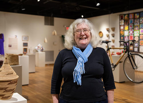 Susan Rodgers stands in an art gallery full of handmade crafts
