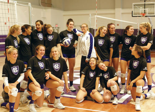 Allie Barry '19 (holding volleyball) and head coach Melissa Batie-Smoose (in white) along with this season's volleyball team in the Hart Center at the Luth Athletic Complex.