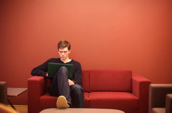 student on a laptop sitting on a red couch