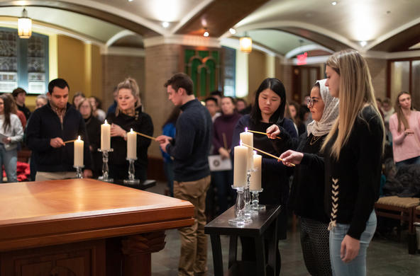 students lighting candles as part of Mass in Mary Chapel