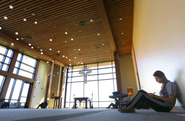 student sitting on the floor in the Joyce Contemplative Center doing homework