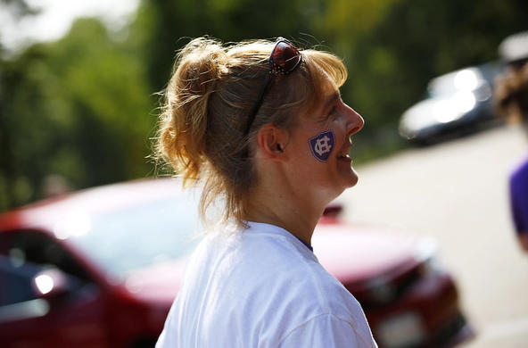 an alumni volunteer with the athletics Holy Cross logo painted on her cheek