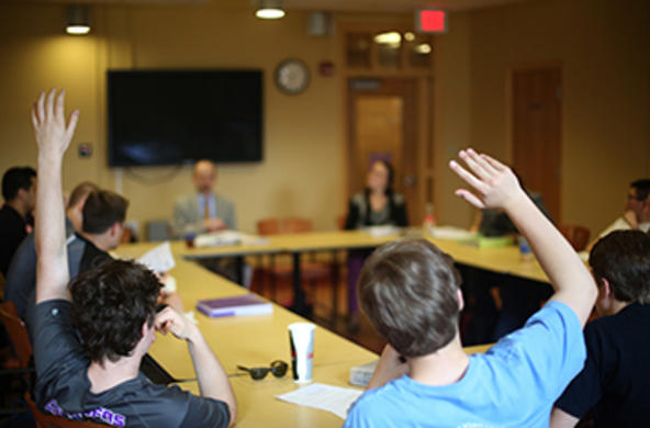 students raise their hand in a classroom