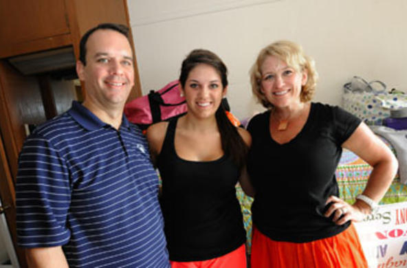 First-year student posing with parents in dorm room during move-in day
