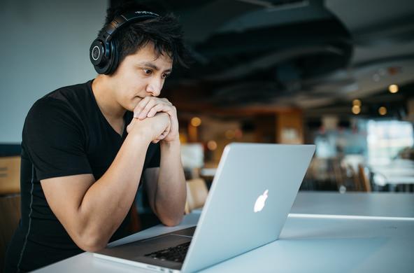 Person wearing headphones and looking at a laptop