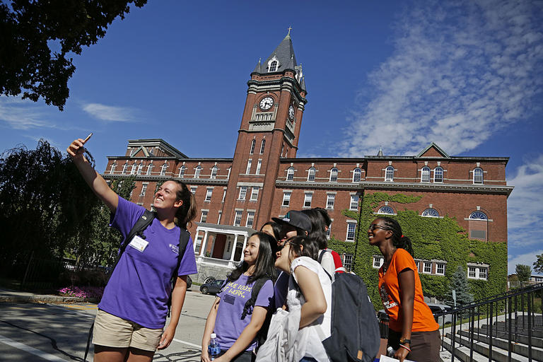 group of students taking a selfie near Dinand Library stairs with O'Kane Hall in the background