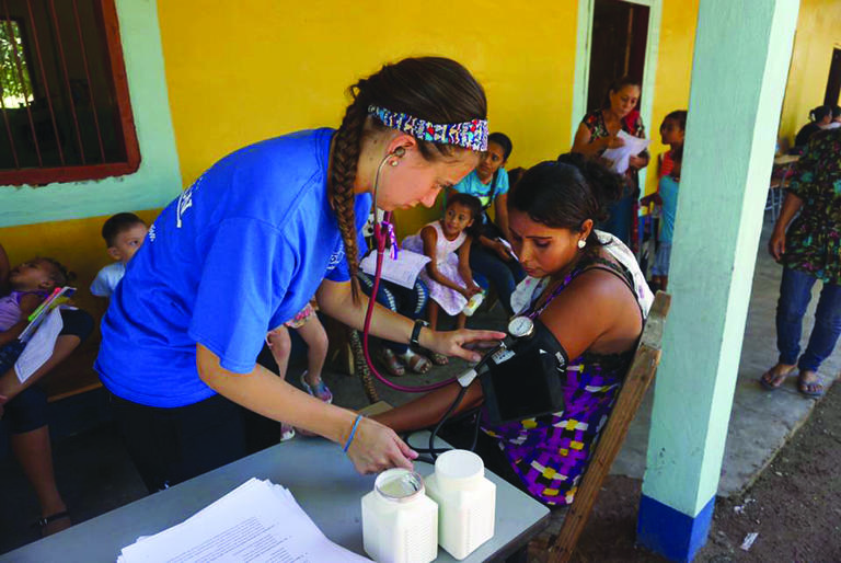 a student on an immersion trip takes a blood pressure reading