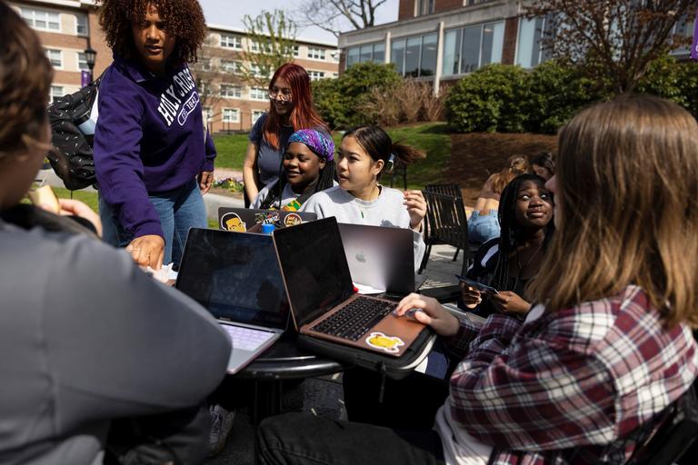Students gathered outside on campus with laptops