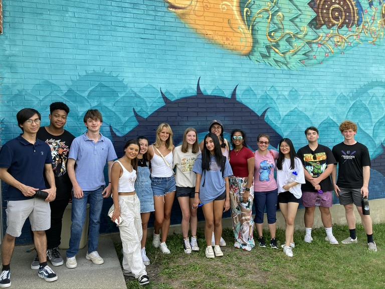 Group of students standing in front of a mural.