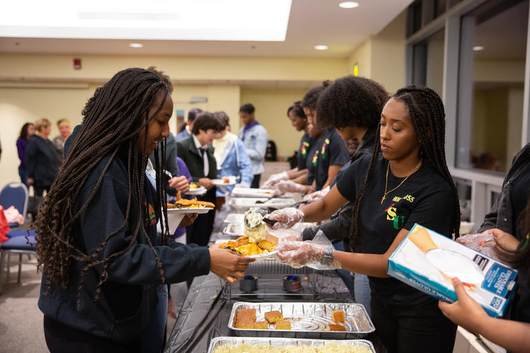 Student serving food to a guest at the Black Student Union Fish Fry