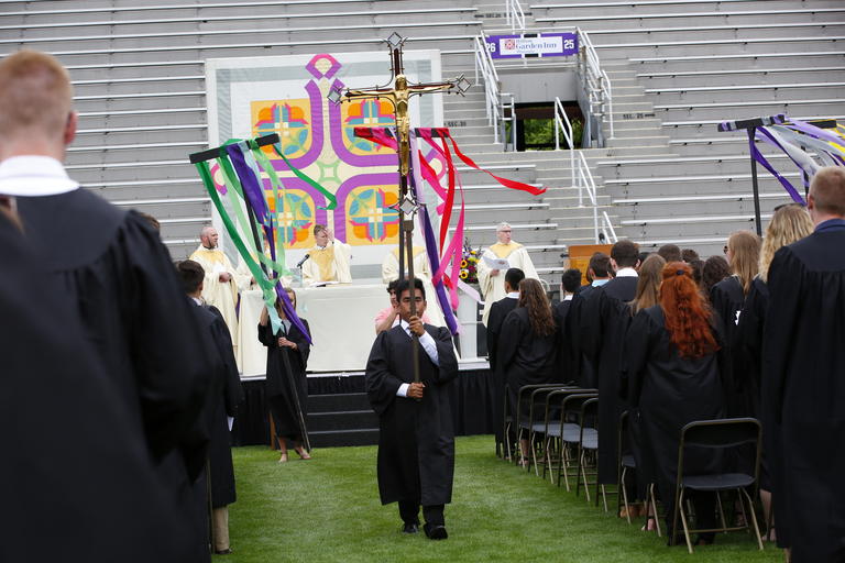 Graduate carrying banner down aisle during mass processional 