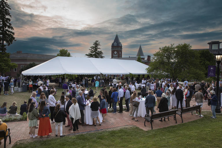 Distance viewed of graduates and their families at a reception on the Hoval at sunset. 