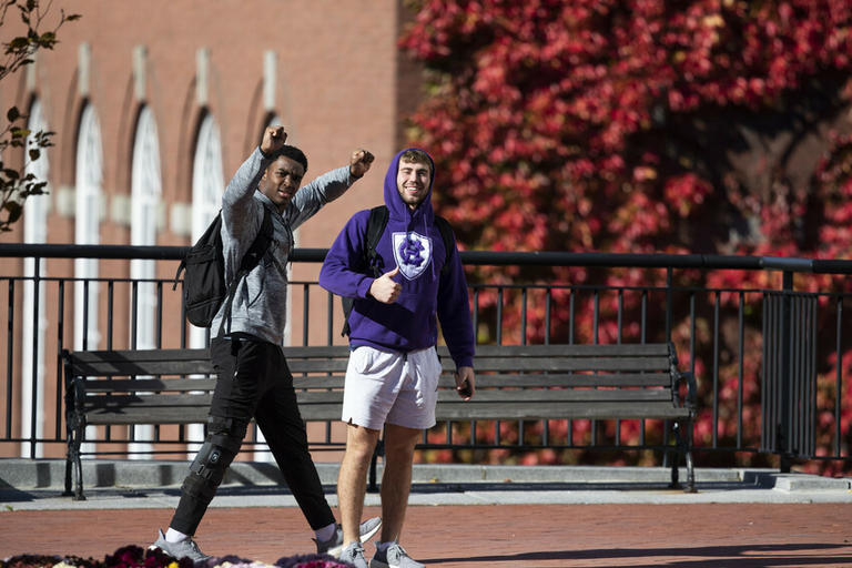 Students walking on campus, raising hands in triumph