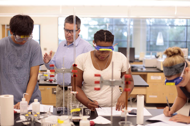 Ken Mills, professor of chemistry, works with students in his lab. 