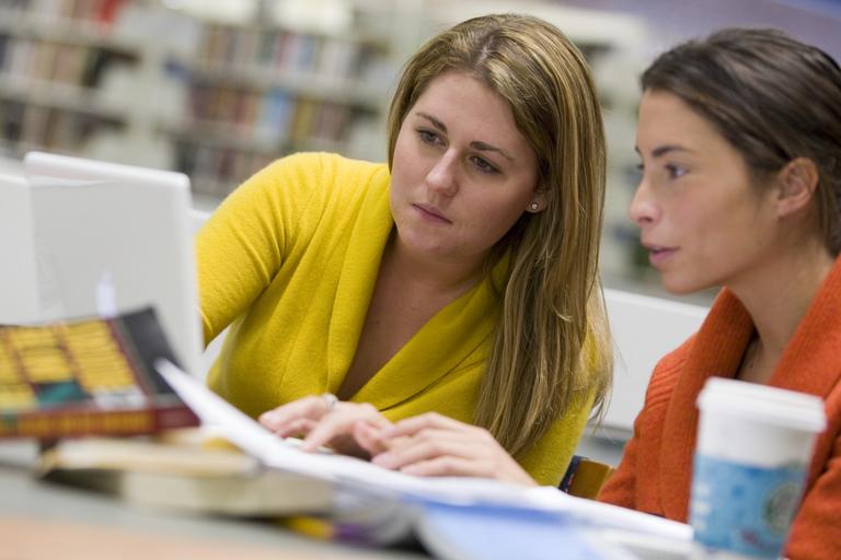 Two women looking at a laptop in a library
