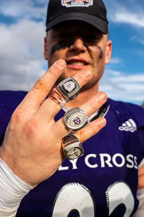 A Holy Cross football player shows off their championship rings