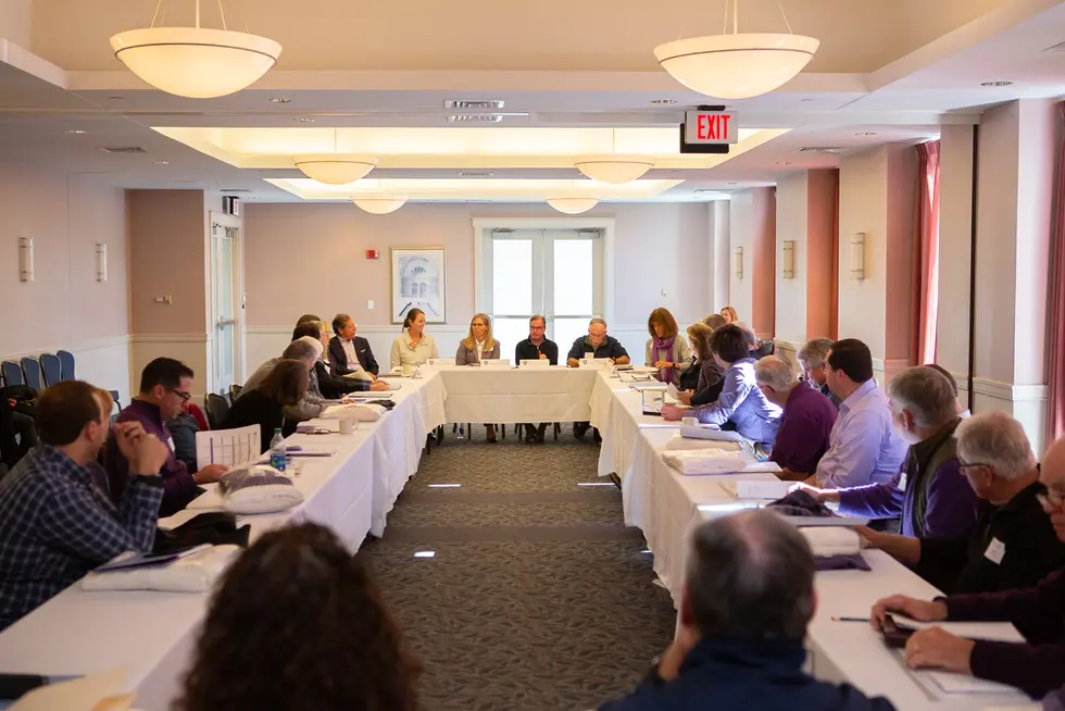 a group of people sitting around a rectangle of tables