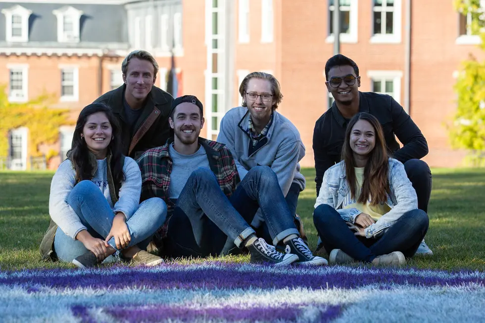 a group of six people sitting in the grass on campus at Holy Cross