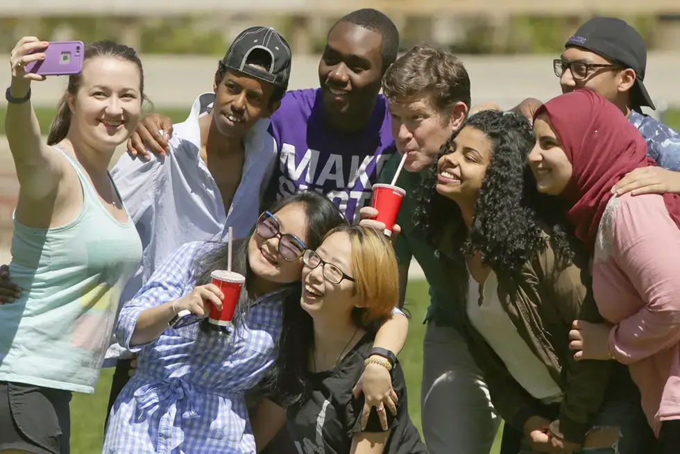 A group of Spanish students take a selfie with a faculty member outside.
