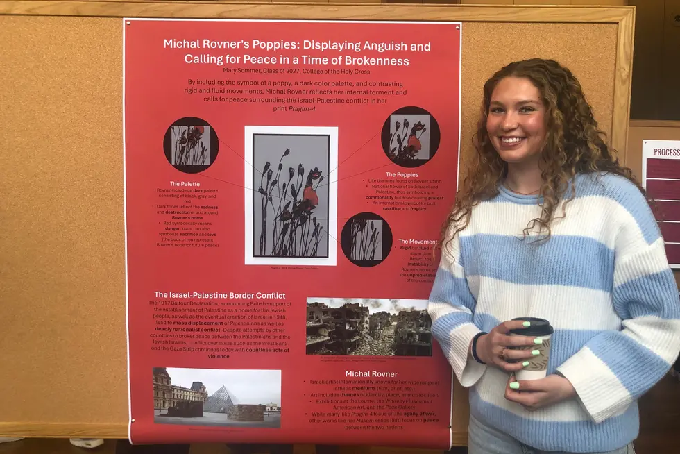 A student standing beside their presented research project at the Academic Conference.