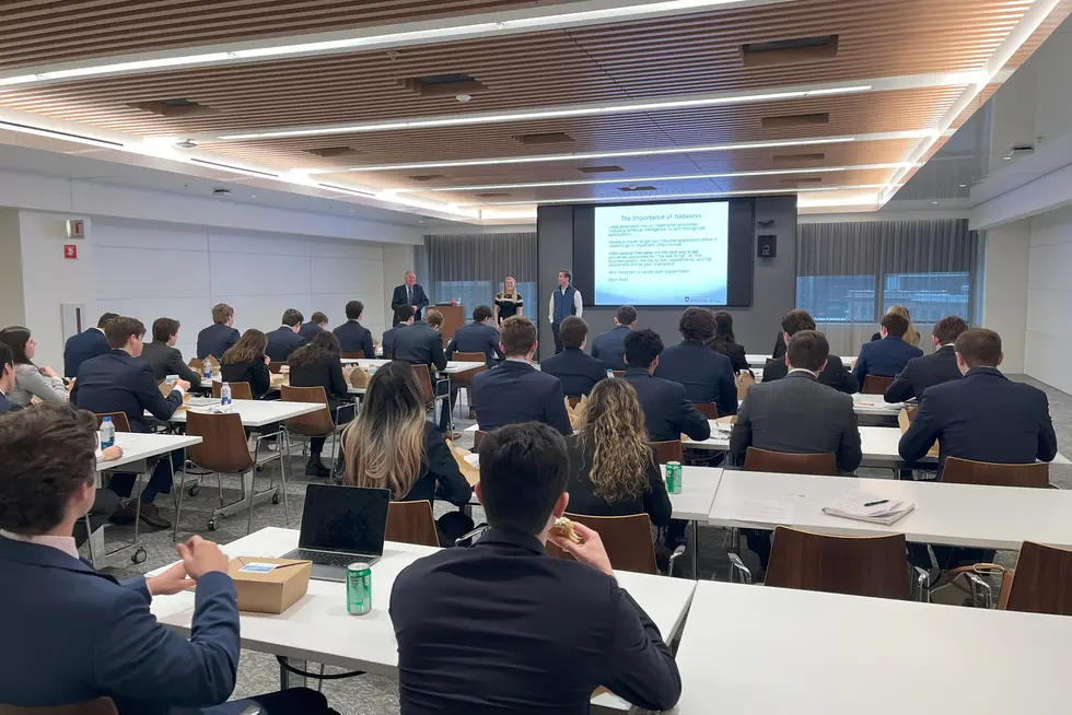 Business students sitting at tables and listening to a lecture.