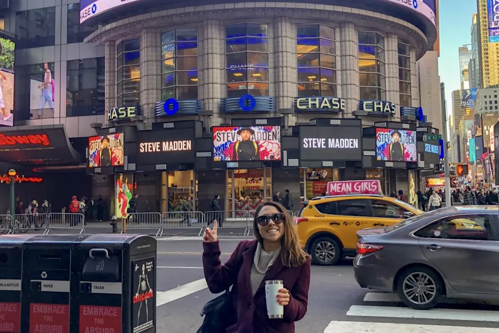 Gina Righini Cipolla poses in front of a billboard in Times Square.