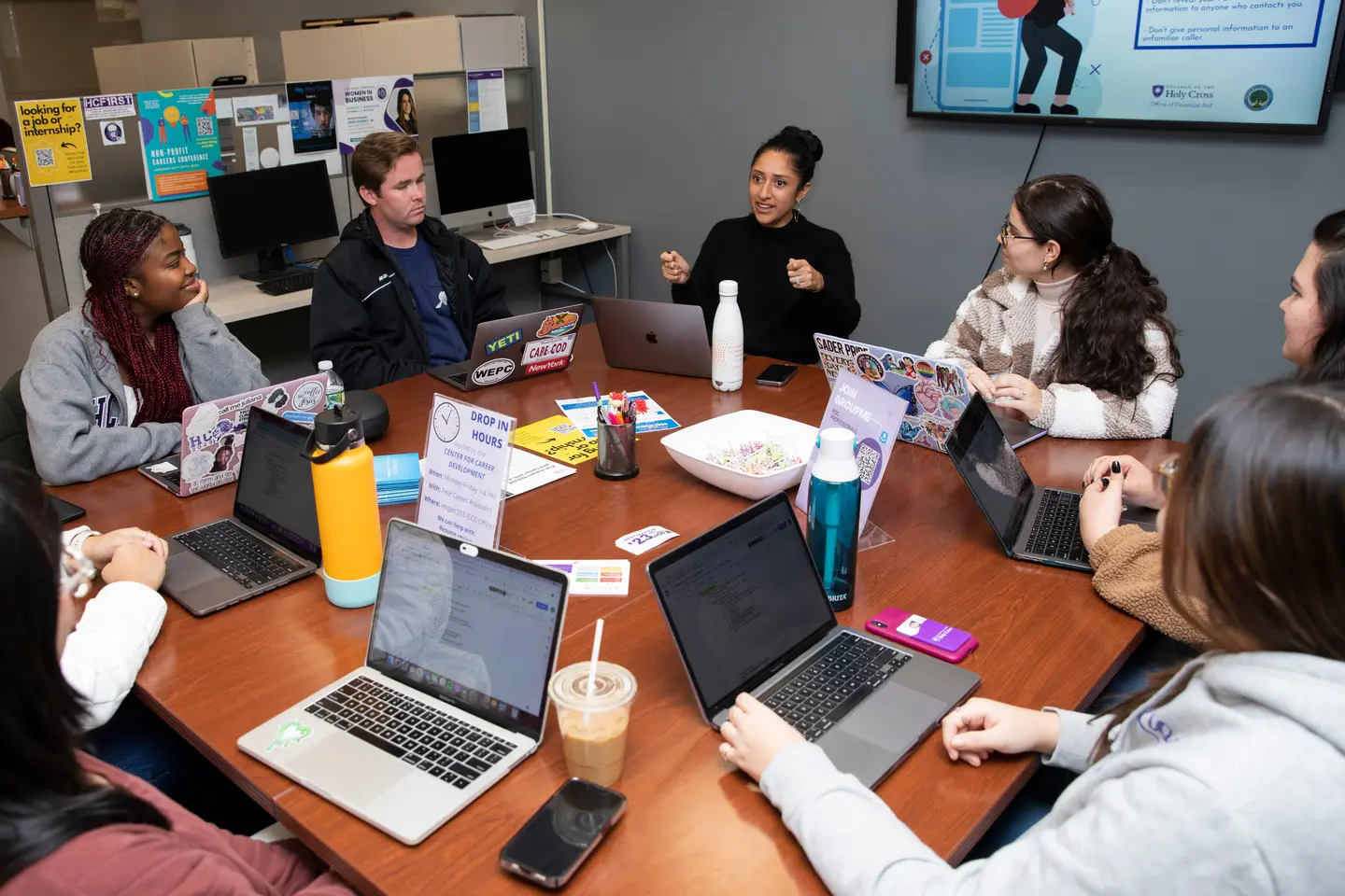 Students sitting in a circle working on a group project with their laptops