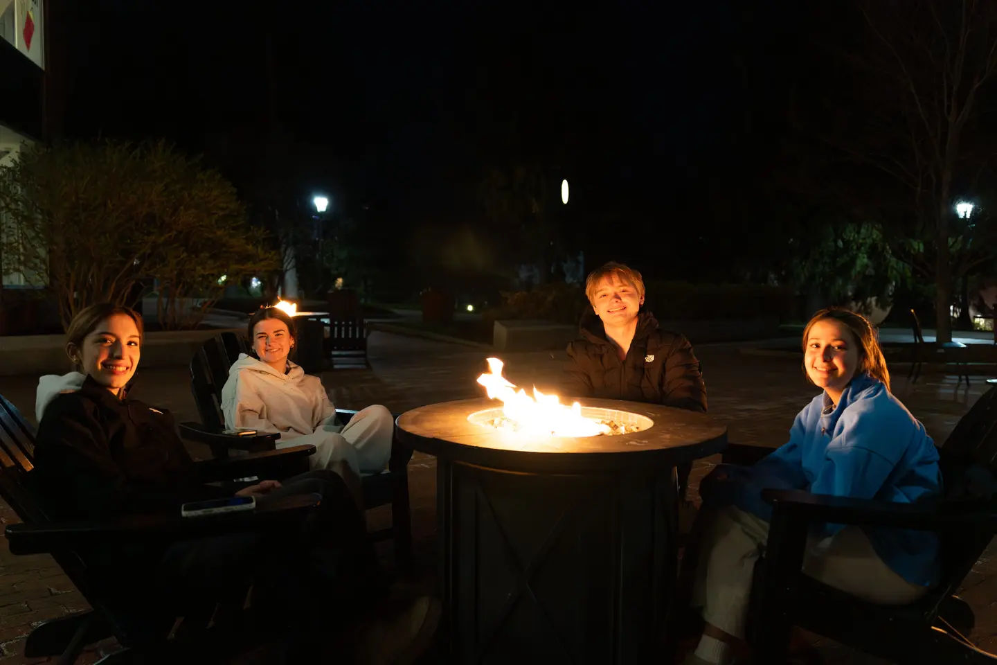 Students sit around a fire pit on the Hoval at Holy Cross
