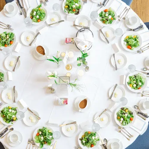 Bird's eye view of circular table with formal table settings.