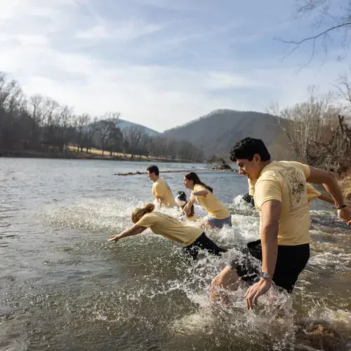 Students dive into a river on the 2026 Holy Cross Spring Break Immersion trip.