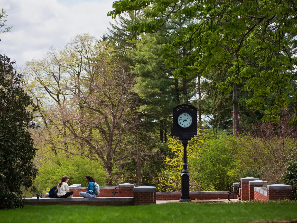 Two students talk underneath the Holy Cross clock