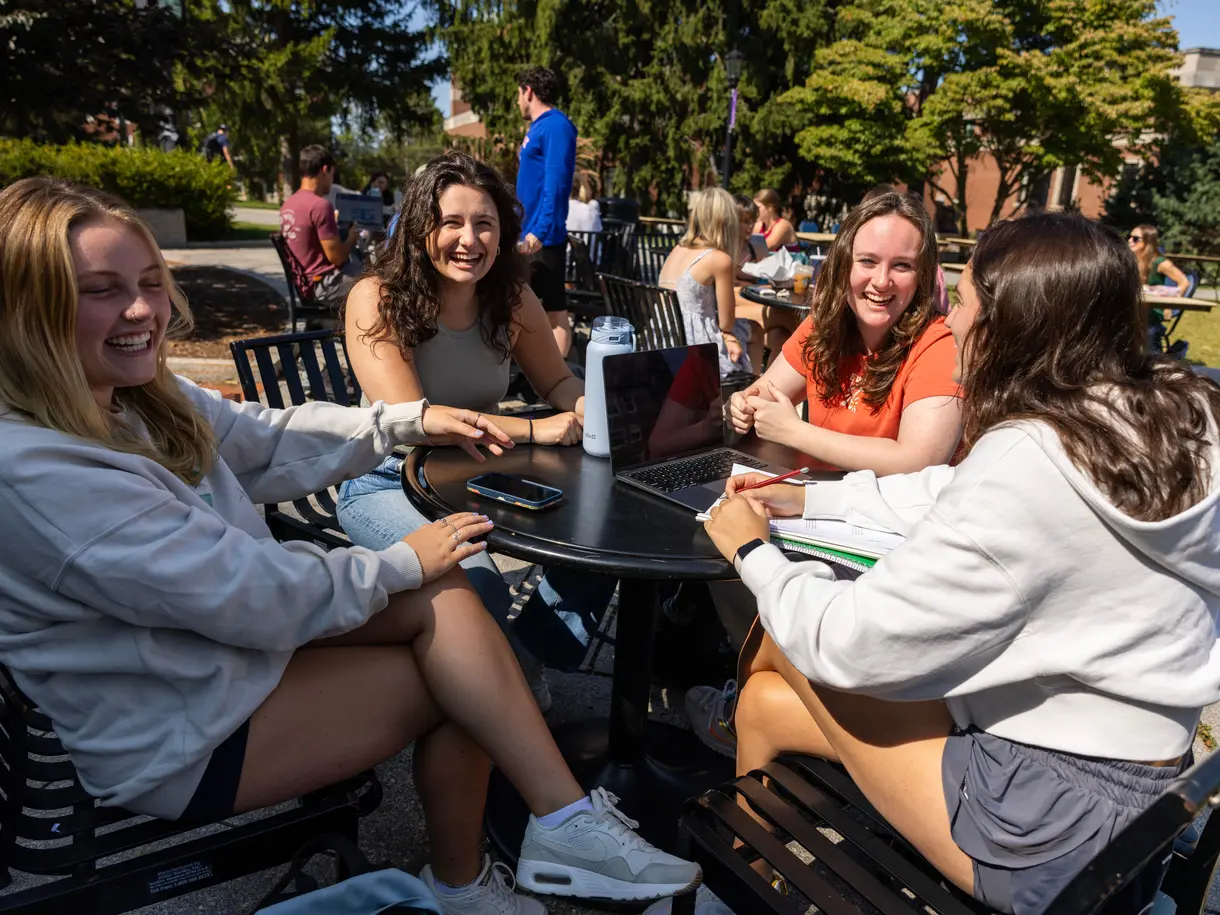 Group of 4 students laughing around a table