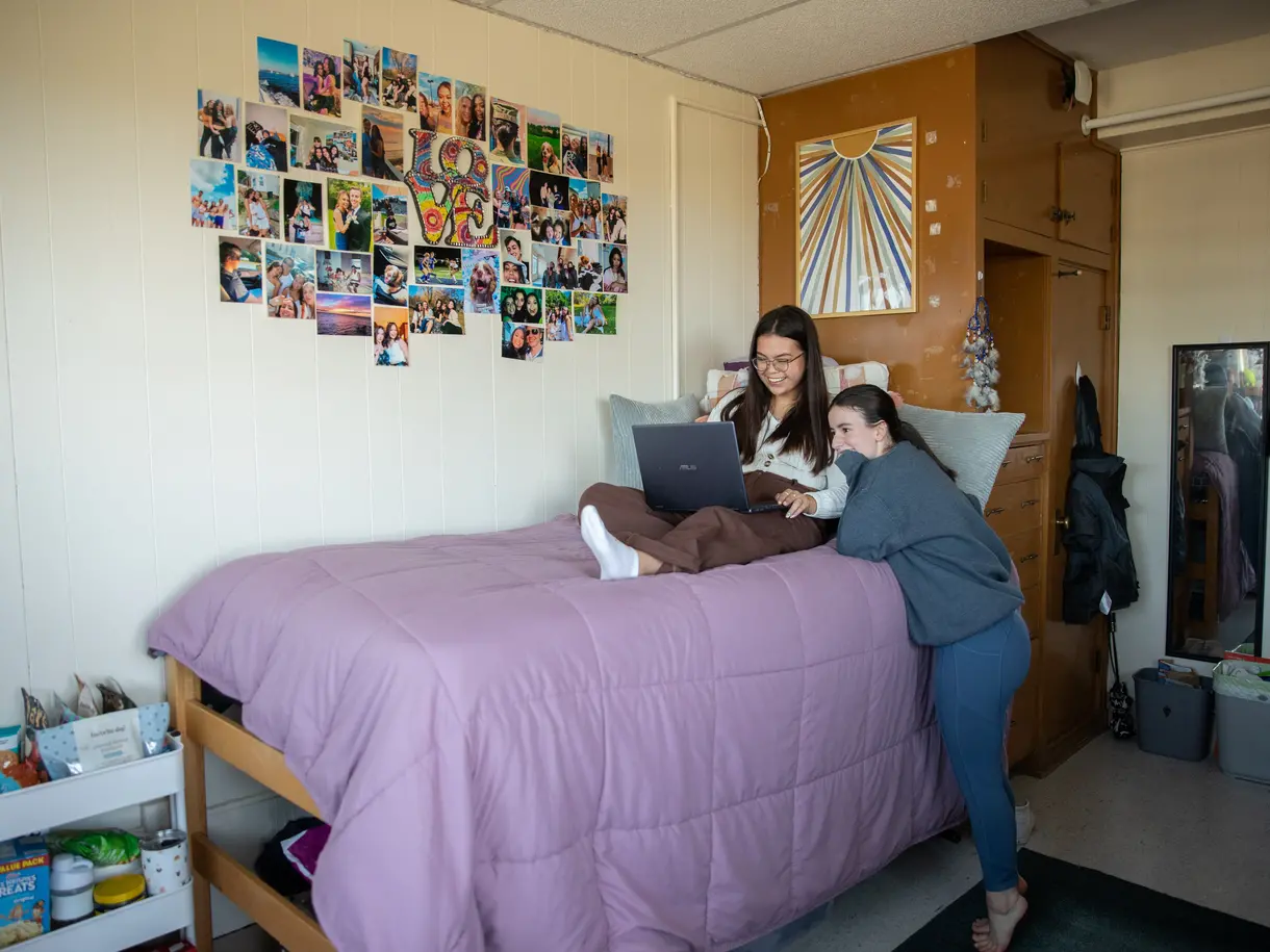 Students hang out in Lehy Hall, a collage and posters are on the wall