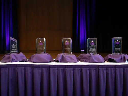 5 glass awards lined up on a table