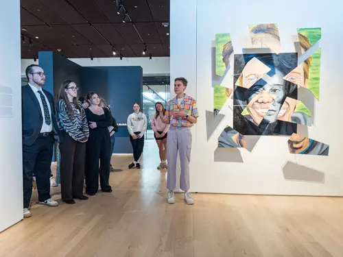 Student presenting their art for senior art exhibition in Cantor Art Gallery.