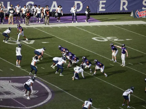 Holy Cross football players set up to run a play against opposing team