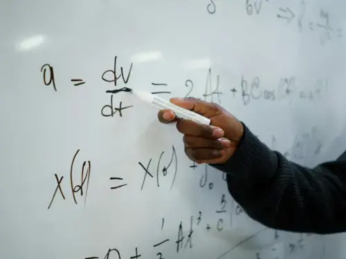 Hand pointing at equation on whiteboard 