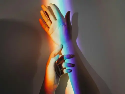 Outstretched hand with rainbow beam of light cascading across it